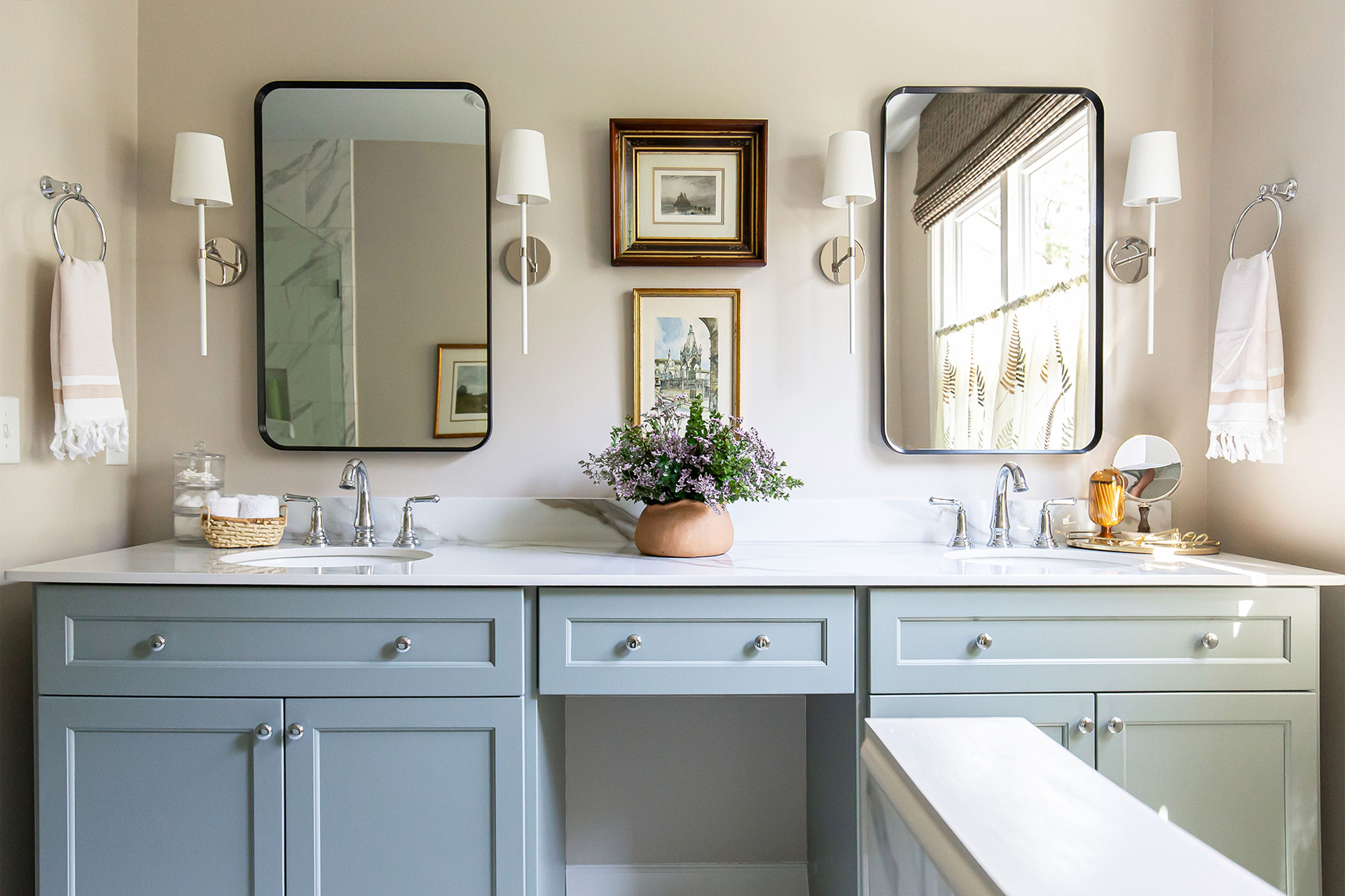 A serene and refined primary bathroom in Brentwood with double vanity, soft blue cabinetry, porcelain countertops, dual mirrors, and elegant sconces.