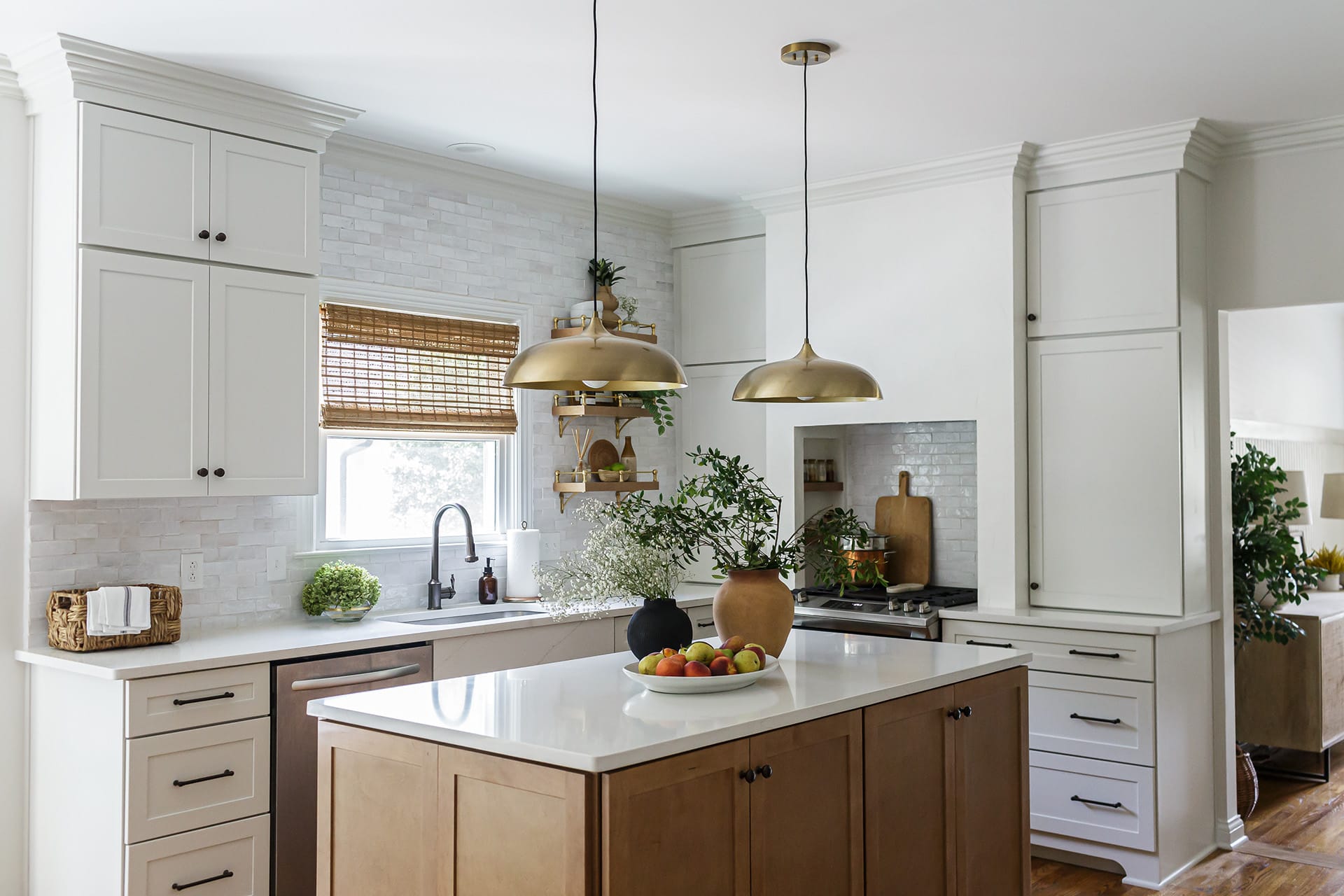 Modern kitchen featuring a white hood wall with open shelving, gold pendant lights, and a natural wood island topped with white quartz.