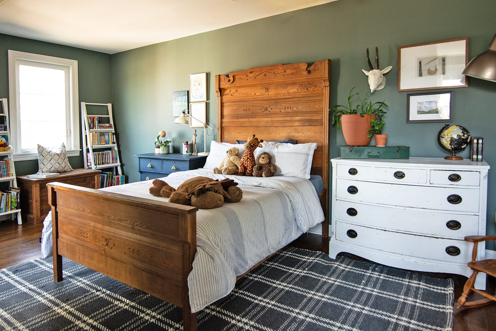 Vintage-inspired kid's bedroom with green walls, wooden bed frame, and white dresser.