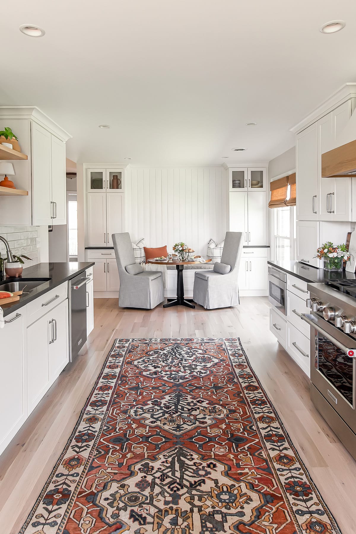 Farmhouse kitchen featuring an oriental rug runner, white cabinetry, a cozy breakfast nook, and warm natural accents.