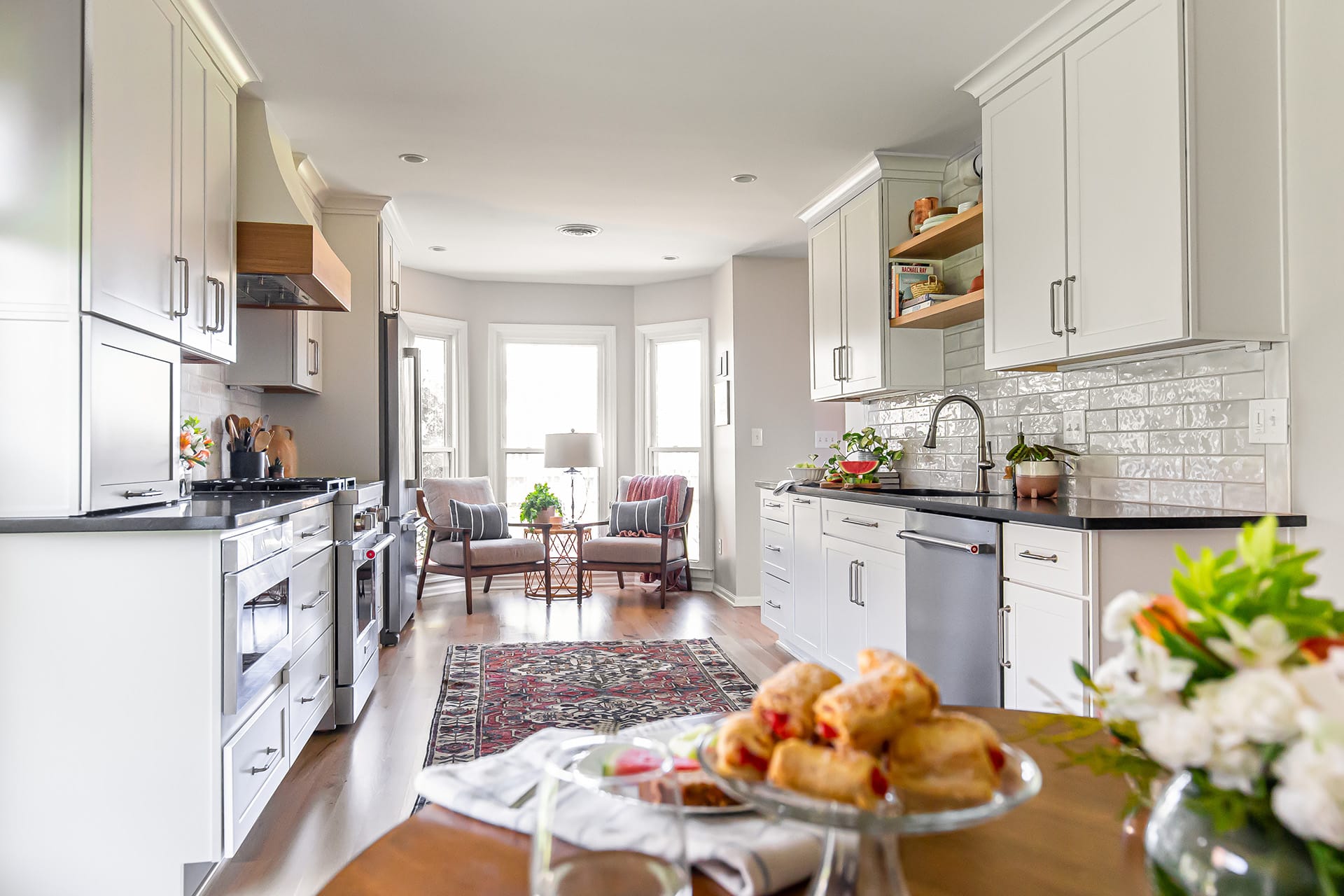 Farmhouse kitchen with a bright seating area, modern white cabinets, and a decorative oriental rug.