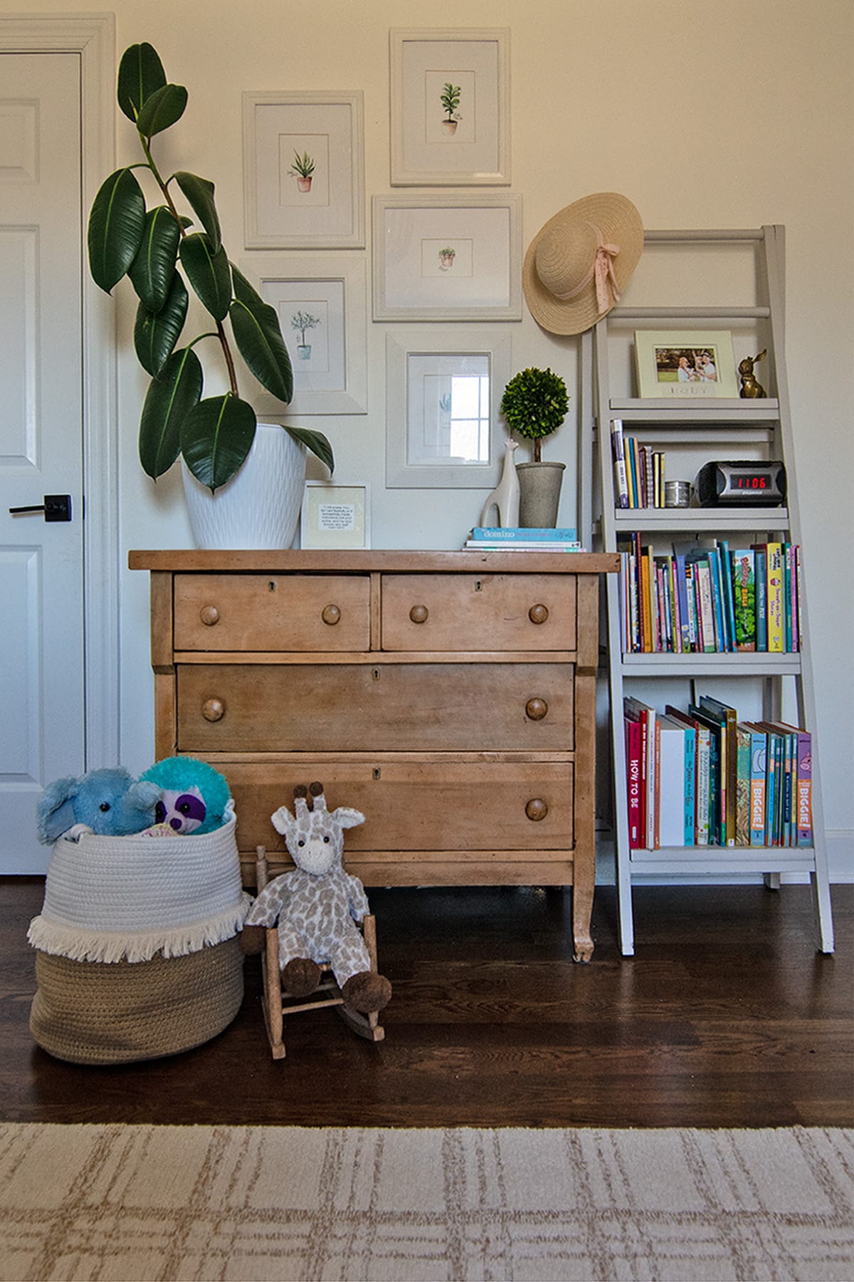 Rustic wood dresser with framed botanical prints, a bookshelf, and decorative accents in a girl's bedroom.