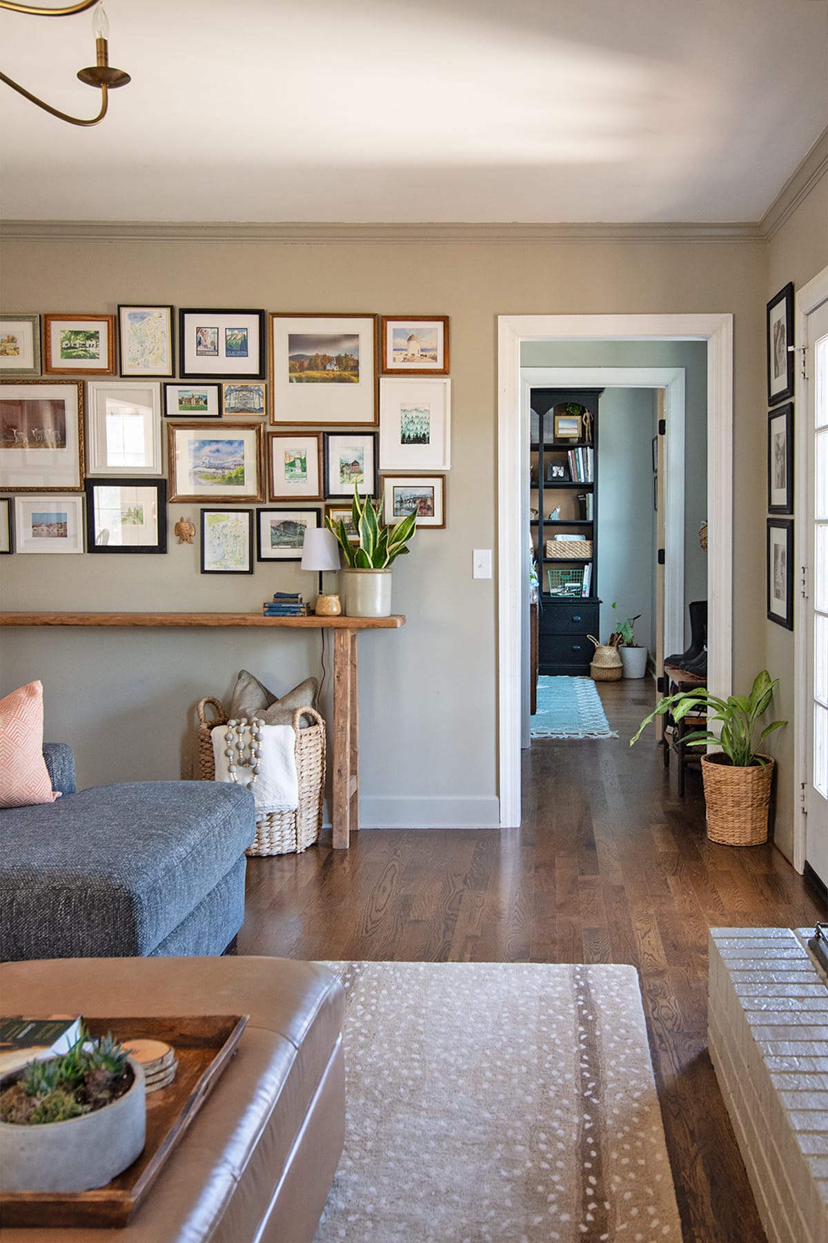 Cozy hearth room with gallery wall, wood console table, and view into hallway with built-in shelving.