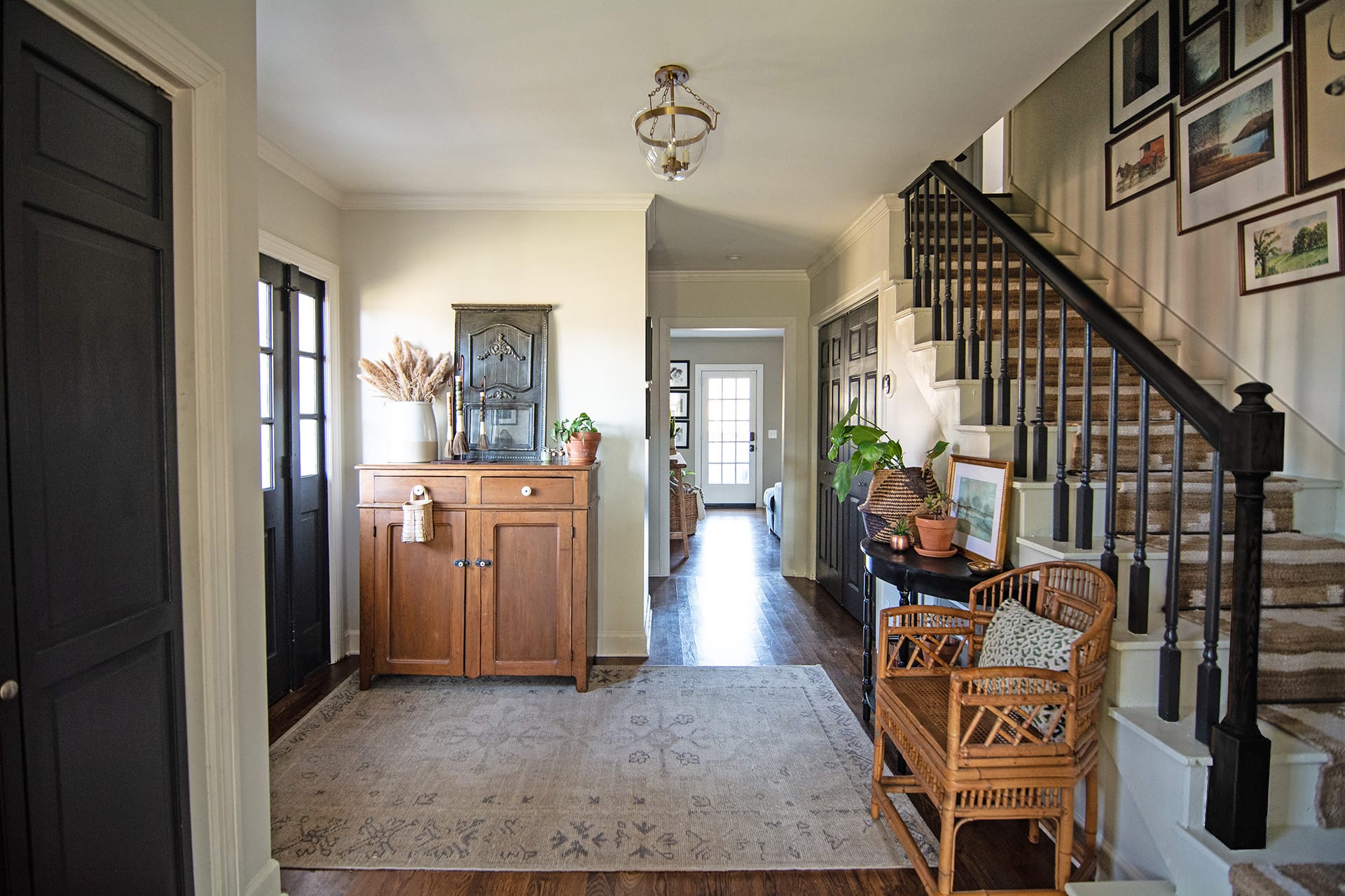 Charming colonial foyer with a wooden cabinet, gallery wall, and staircase.