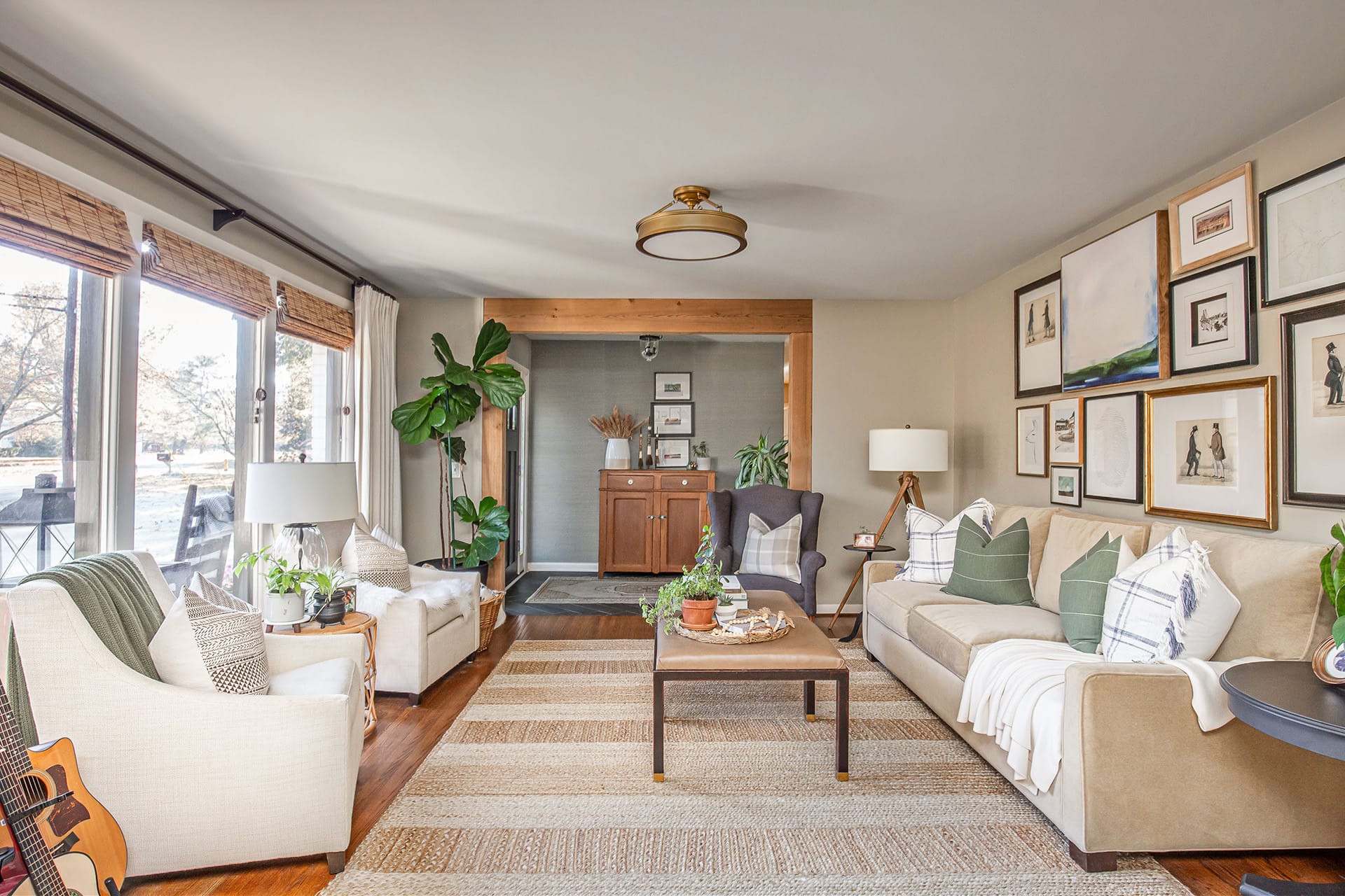 A warm and inviting living room featuring a gallery wall, natural light from large windows, neutral furniture, and layered textures.