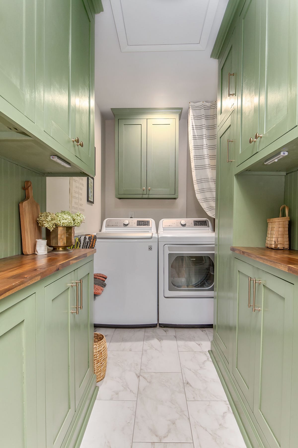 A charming laundry room featuring green cabinetry, white appliances, and a butcher block countertop with a polished wood finish.